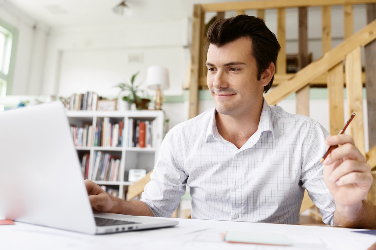Male architect with computer studying plans in office